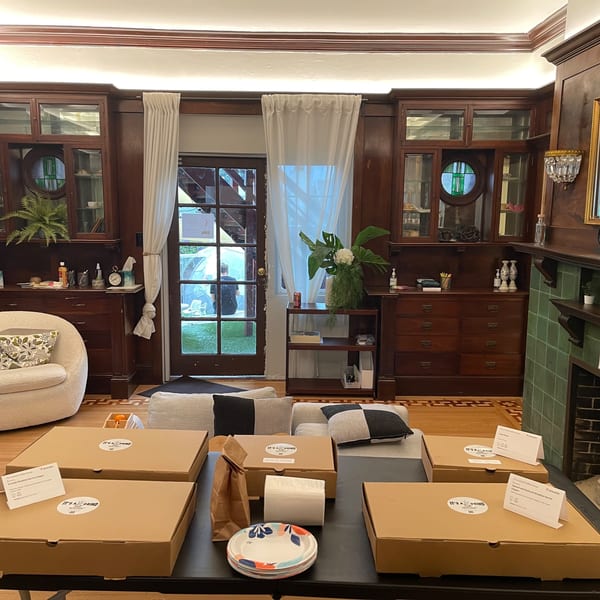 A room with dark wood paneling, a fireplace, and several "It's a Grind" catering boxes on a table.