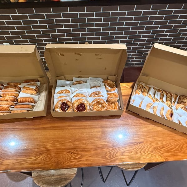 Three open cardboard boxes filled with various pastries on a wooden table.