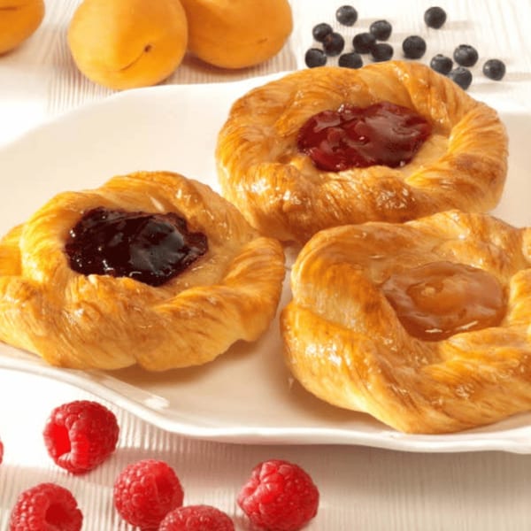 Three fruit danishes with raspberries, blueberries, and apricots on a white plate.